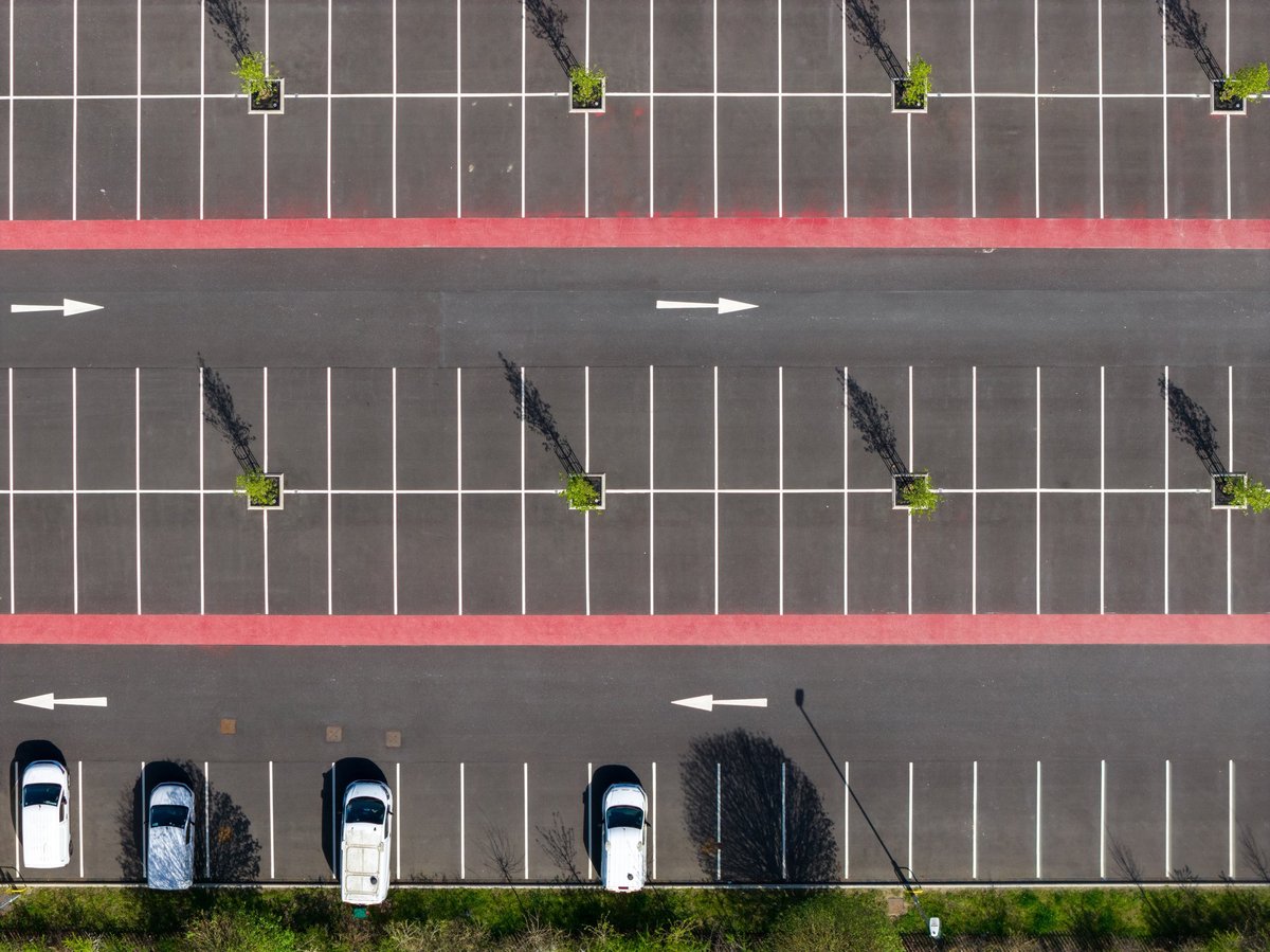 Aerial view of a parking lot with crisp white markings and directional arrows guiding traffic flow