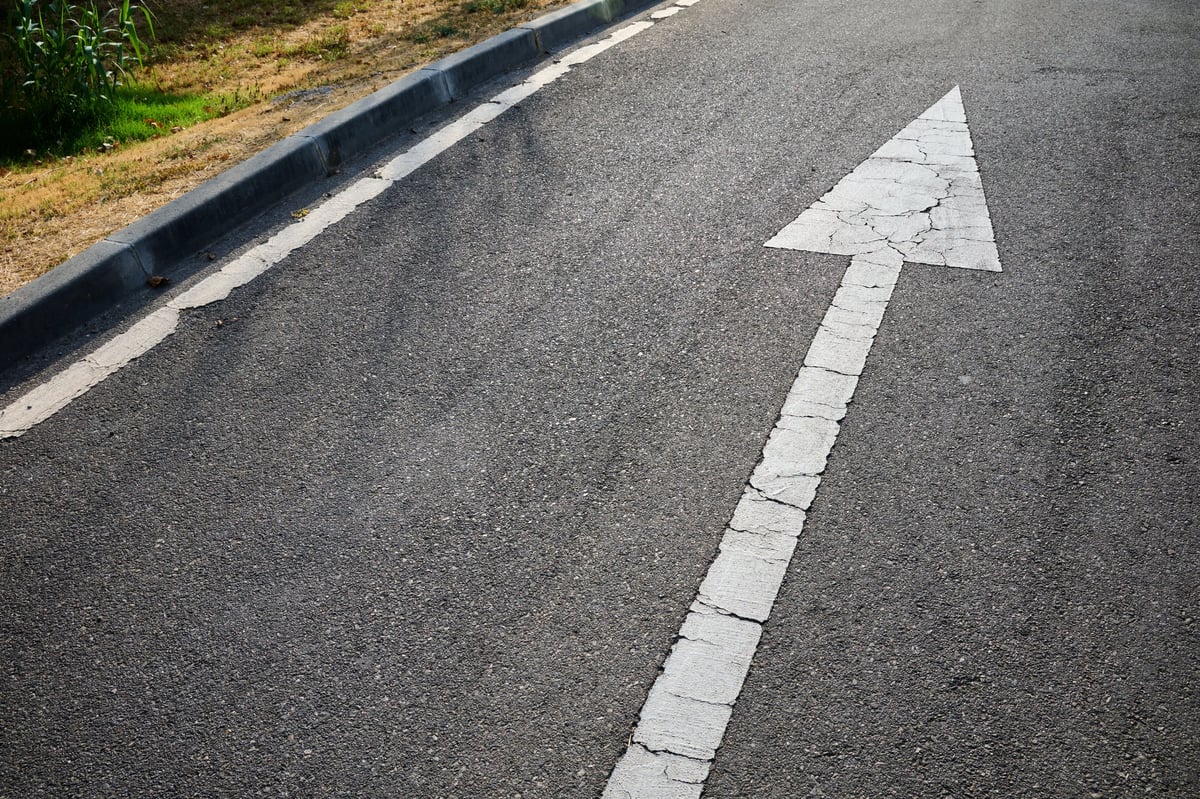 White directional arrow painted on the asphalt guiding traffic flow