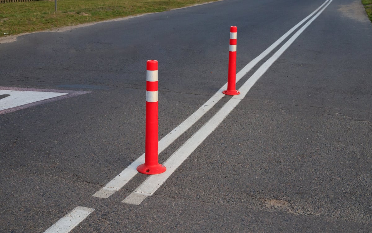 Red flexible traffic delineators mounted on clean parking lot asphalt between white lines