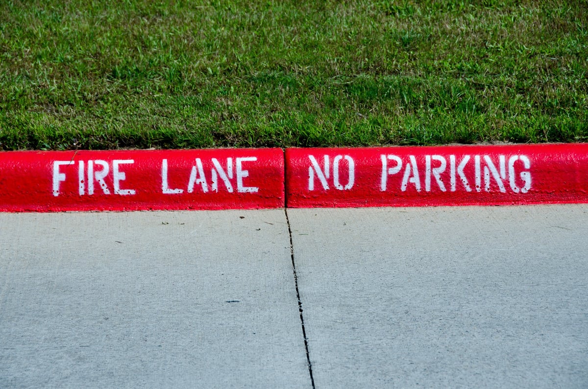Freshly painted red fire lane curb with white lettering